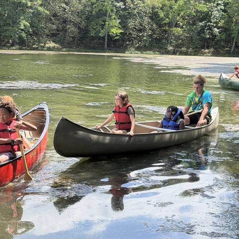 Campers paddling canoes on the lake