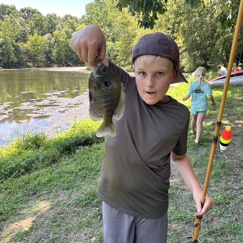 Camper holding up a fish by the lake
