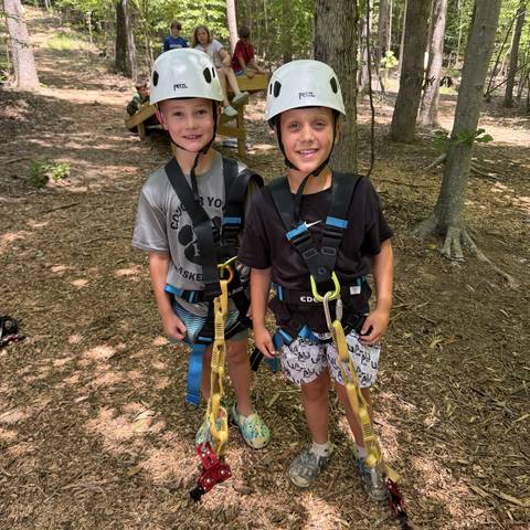 Two campers in climbing helmets and harnesses