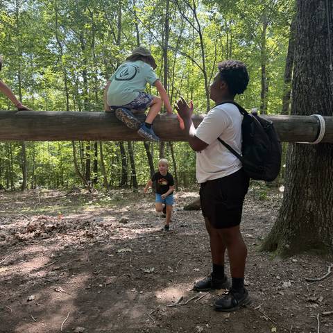 Camper on the high ropes with a counselor spotting