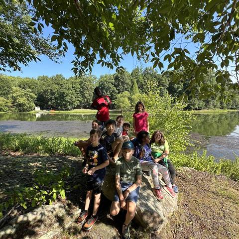 Campers sitting on a log by the lake