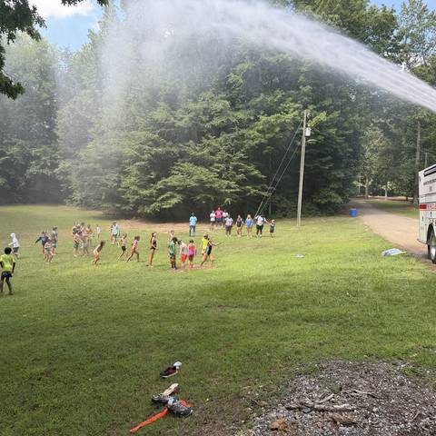 Campers running through the water spray on the field