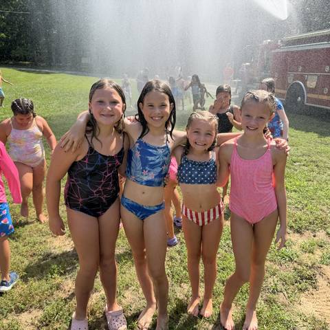 Campers in swimsuits by the water spray
