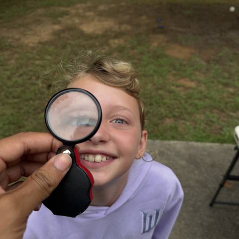 Camper looking through a magnifying glass